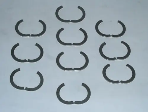 Zehn segmentförmige Ringe aus Metall, die typischerweise in Daikin-Produkten verwendet werden. Sie sind halbmondförmig und in einer ordentlichen Anordnung auf einer Fläche dargestellt.